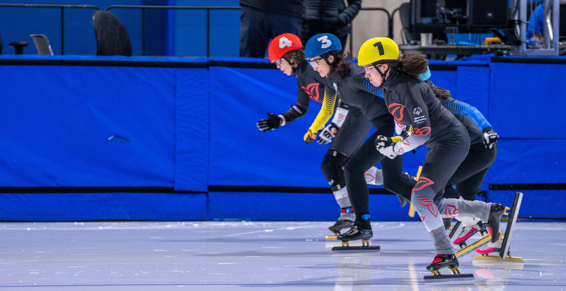Trois patineurs de vitesse participent à une course.