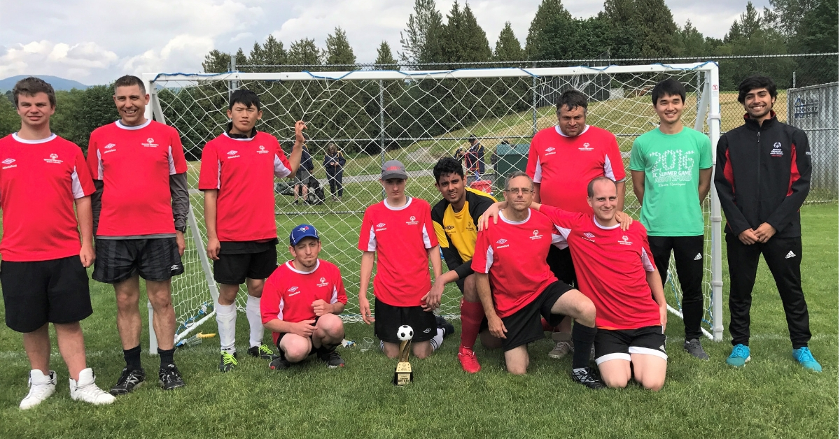 Roshan Gosal poses with his Special Olympics Abbotsford soccer team in front of a soccer net.