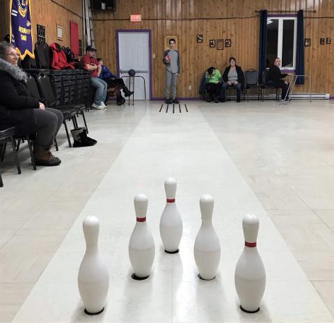 Logan stands at the end of the makeshift bowling alley at the community hall.