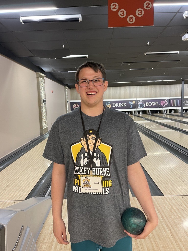 A Special Olympics athlete at the bowling lanes, holding a bowling ball