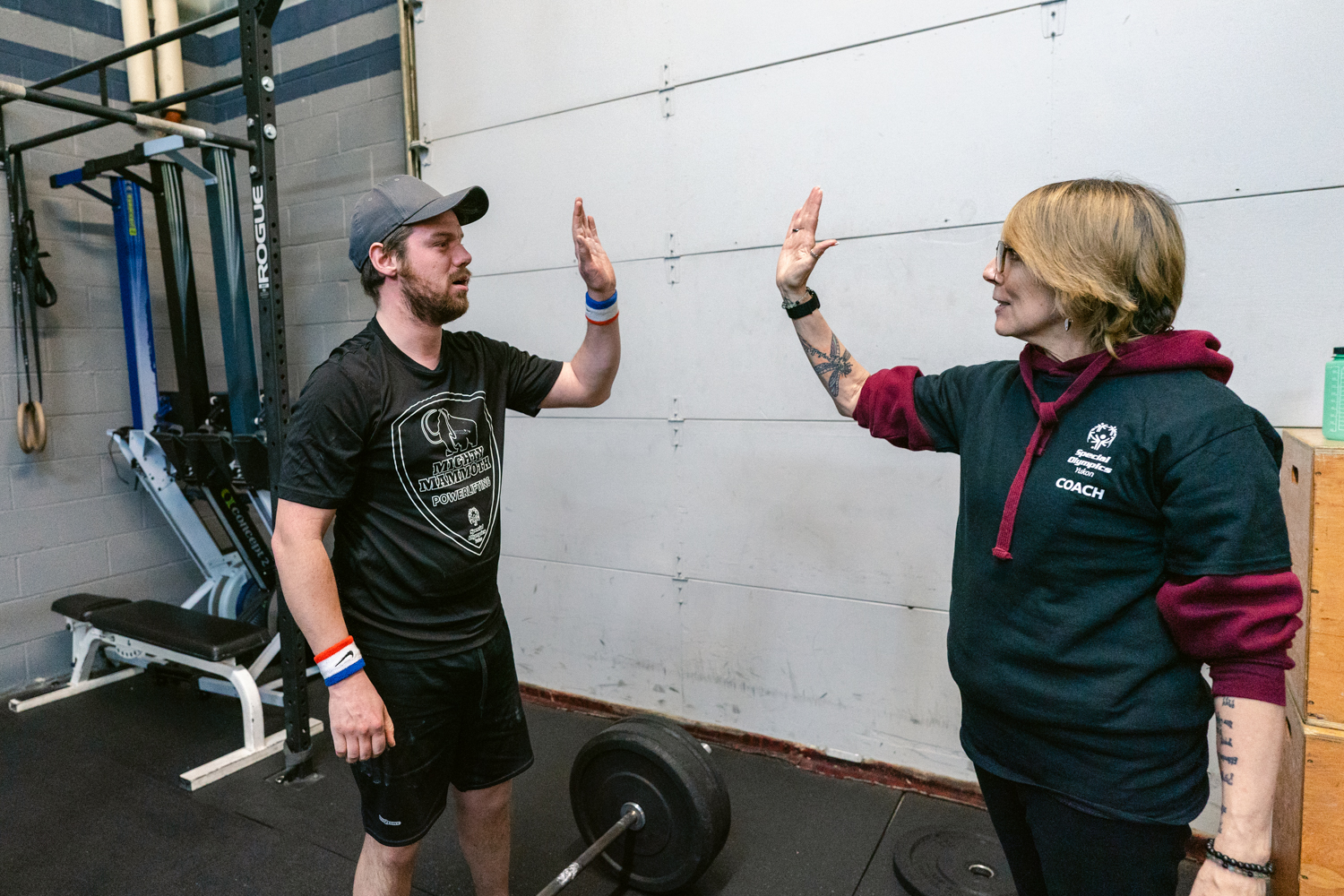 Leah Greenway high-fives athlete Mike Summer during powerlifting practice. Leah Greenway high-fives athlete Mike Summer during powerlifting practice.
