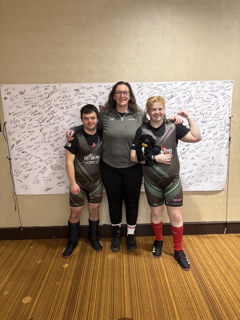2 Special Olympics Powerlifting athletes with their Coach at a competition