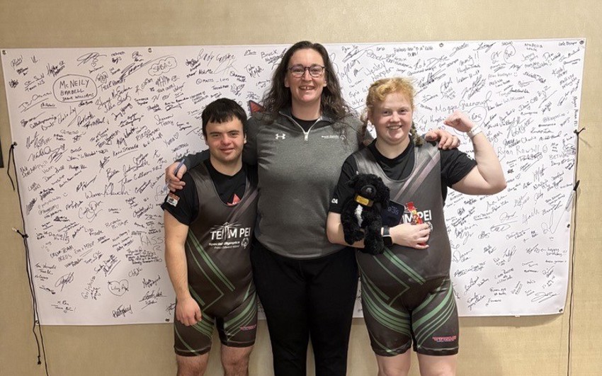 2 Special Olympics Powerlifting athletes with their Coach at a competition
