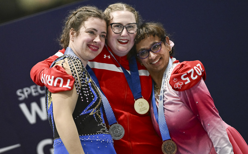Three women in Canadian uniforms hug one another, with medals around their necks. 