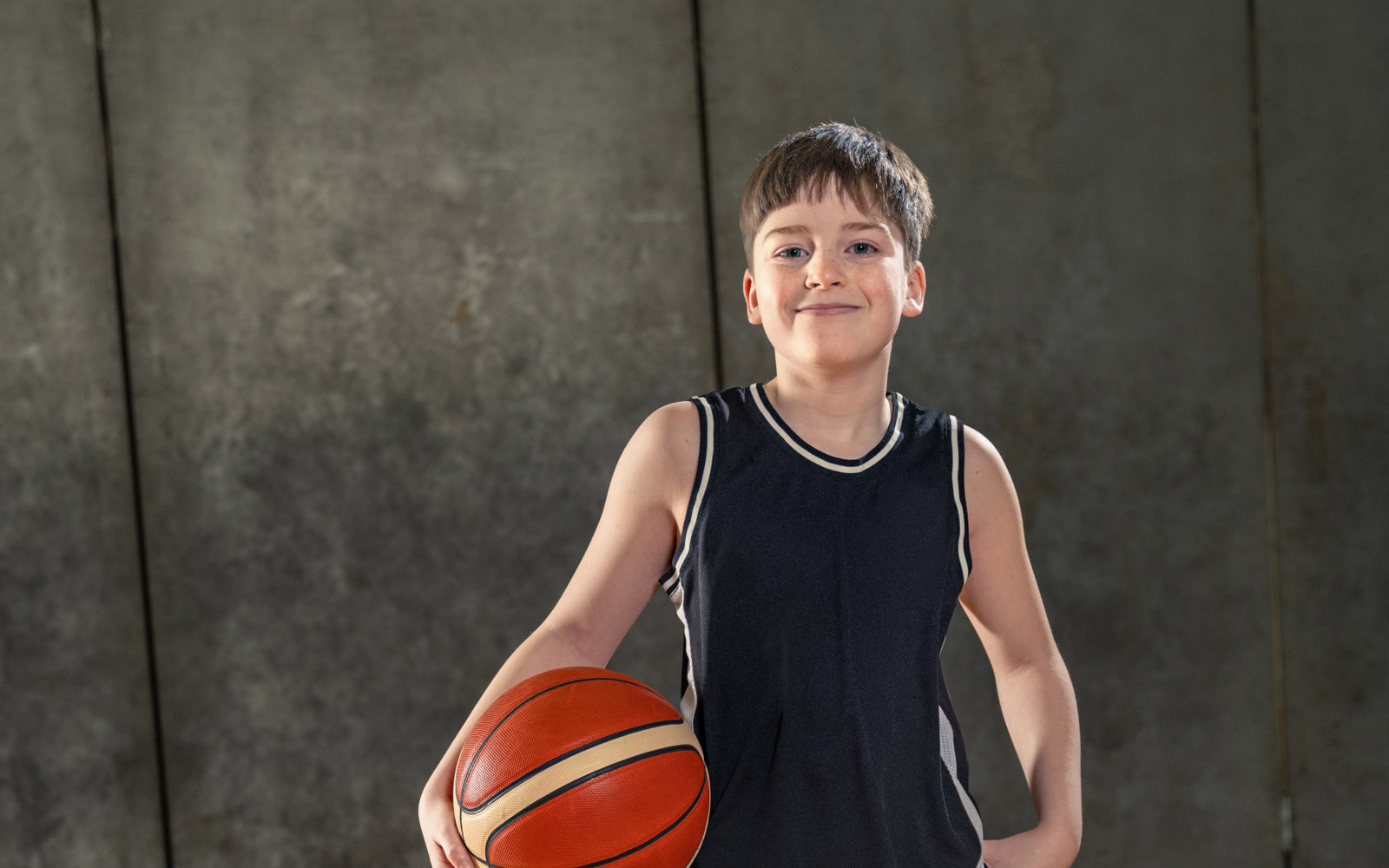 Jeune garçon tout de noir vêtu tenant un ballon de basket