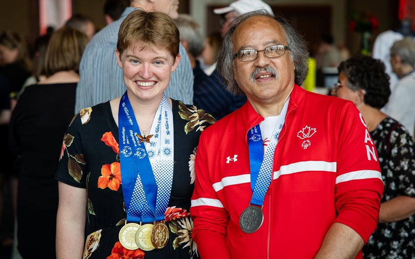 Two Special Olympics athletes standing while wearing medals