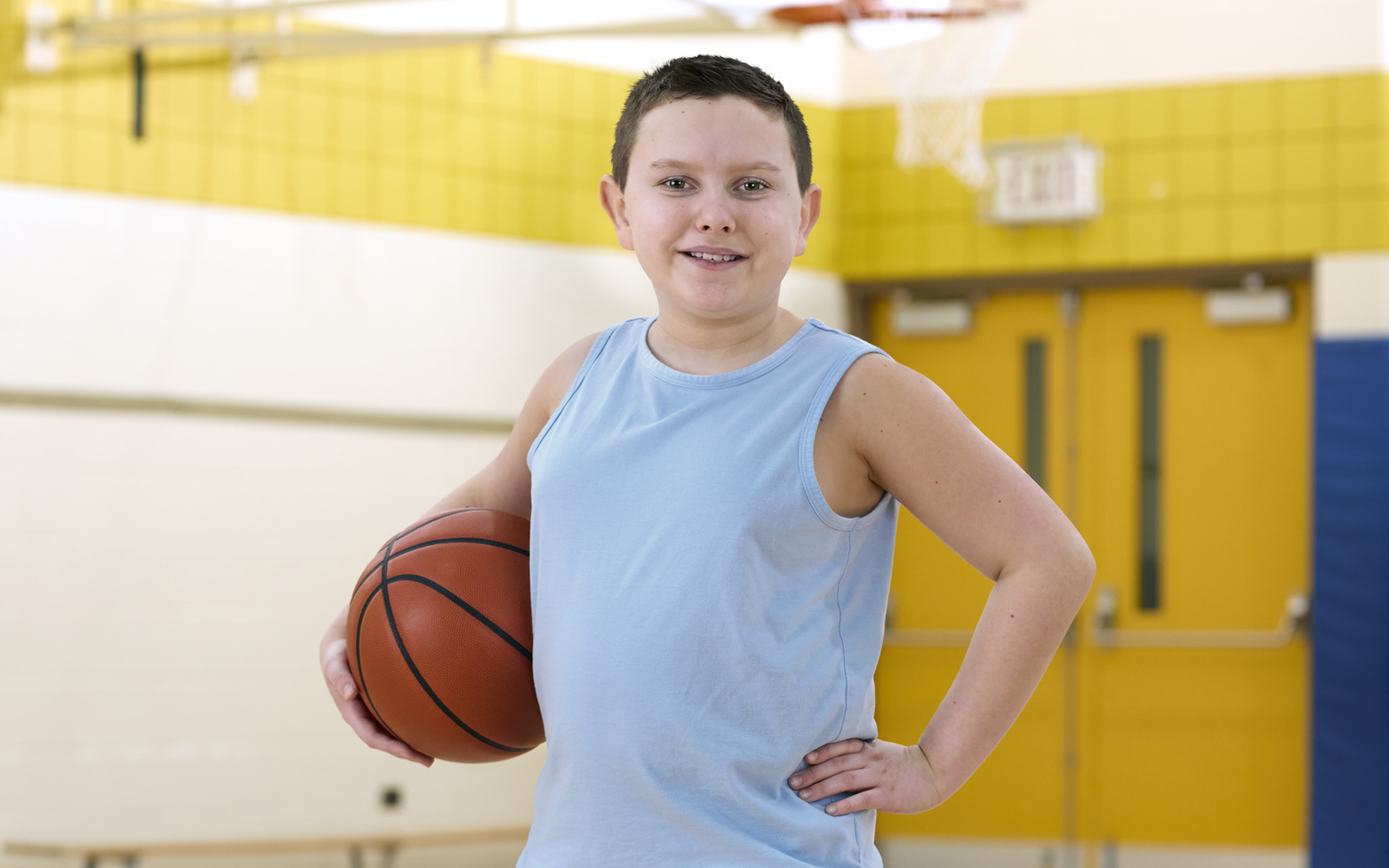 Young boy in blue tank top holding a basketball