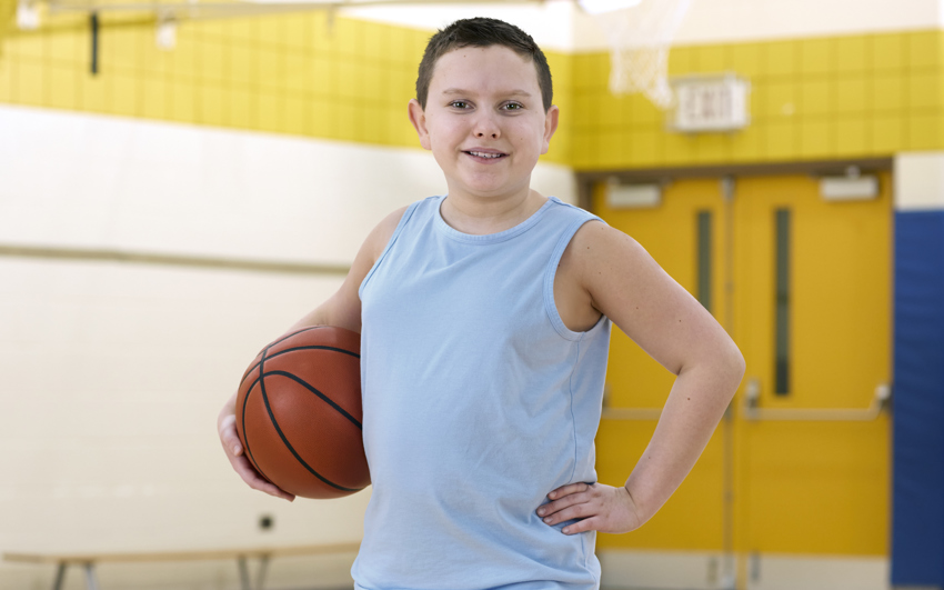 Young boy in blue tank top holding a basketball