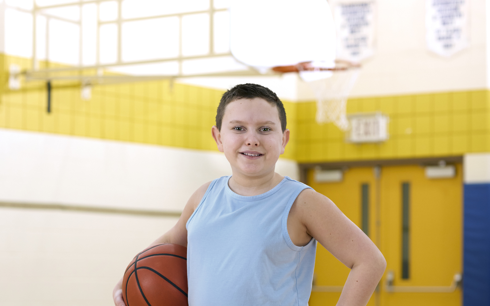 Jeune garçon en débardeur bleu tenant un ballon de basket