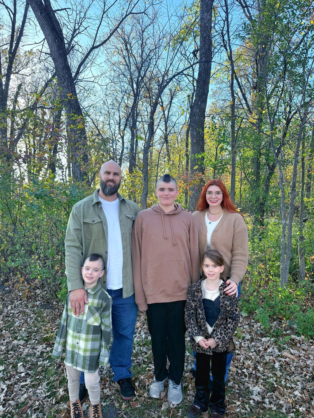 The Von Doelln family posing together on a trail in front of a forested area. 