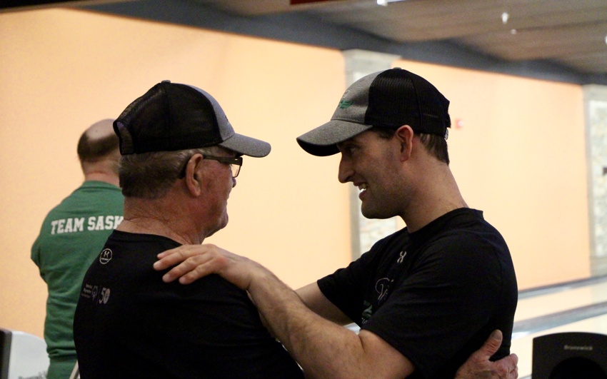 A Special Olympics athlete is supported at bowling by his coach; Rickey Burns