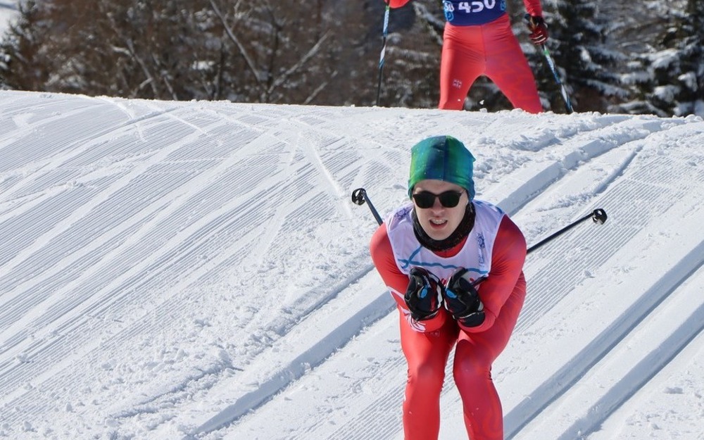 Cross country skier coming down a snowy hill, dressed all in red. 