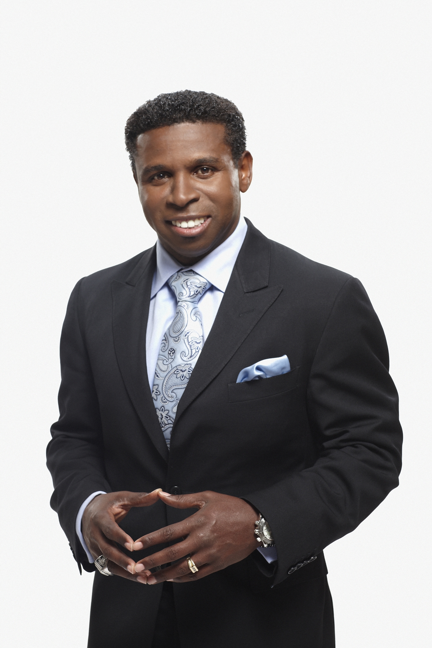Headshot of a man in black suit and blue and white paisley tie. Headshot of a man in black suit and blue and white paisley tie.