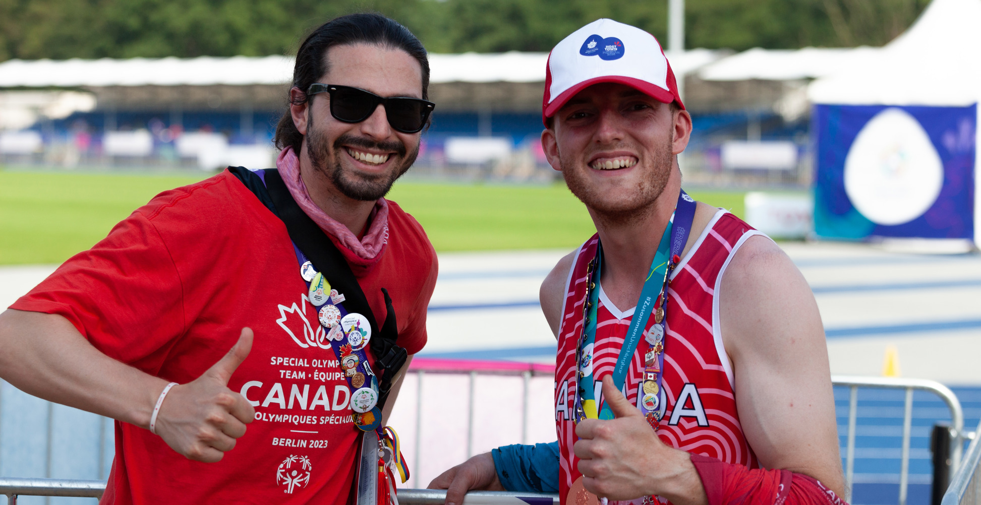 Two men smiling at the camera and giving thumbs up. 