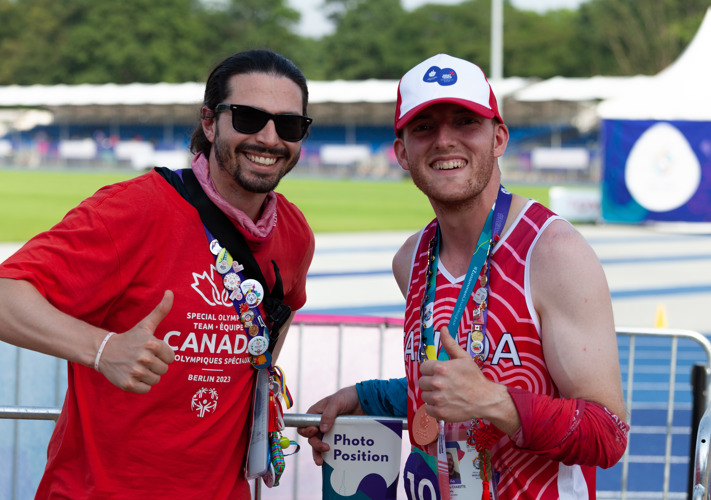 Two men smiling at the camera and giving thumbs up. 