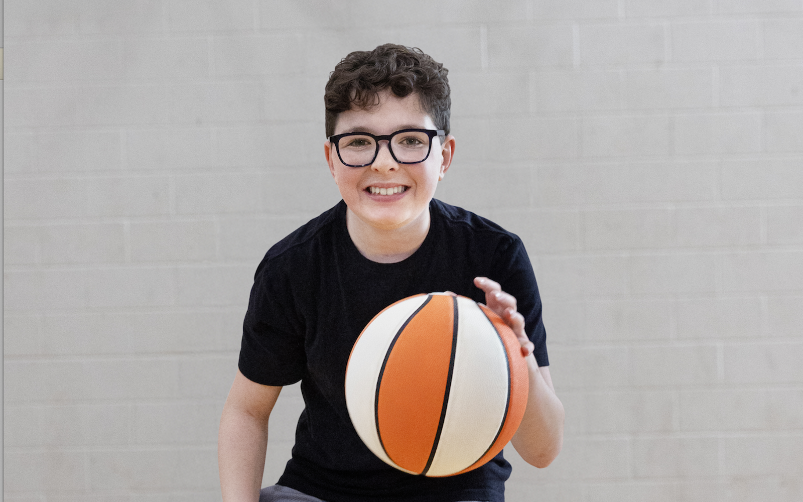 Young man in a black shirt bouncing a basketball 
