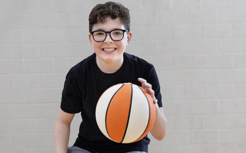Young man in a black shirt bouncing a basketball 