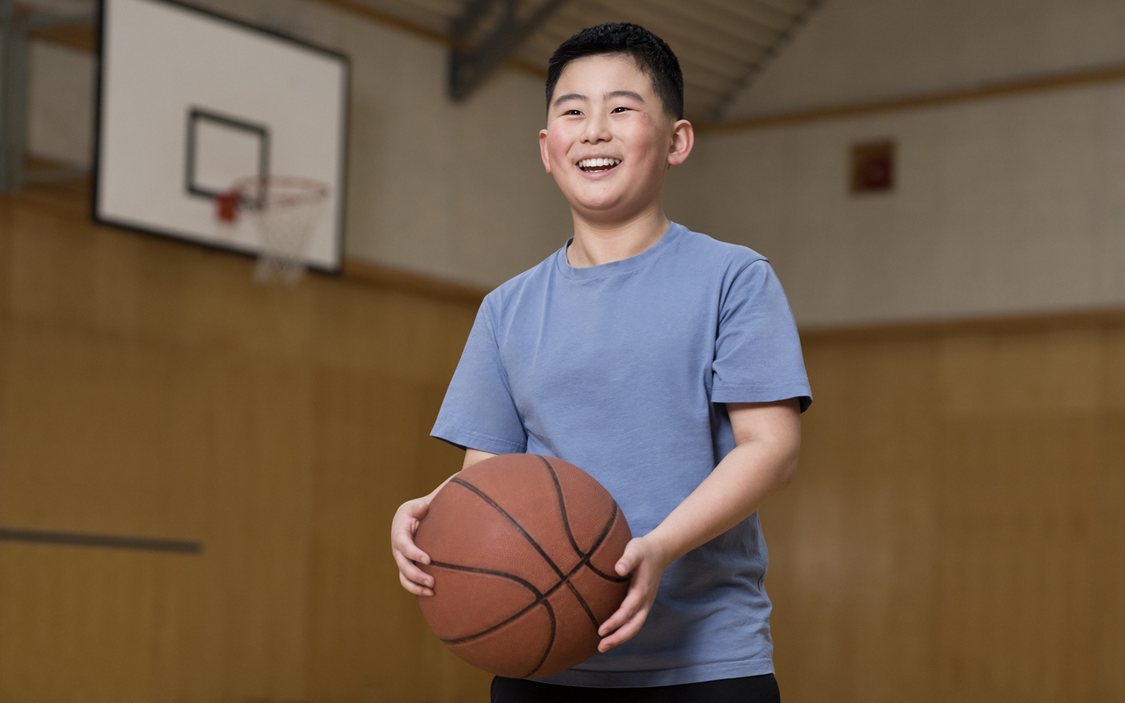 Young boy in blue shirt holding a basketball 