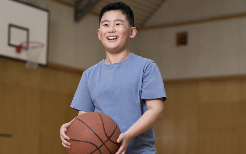 Jeune garçon en chemise bleue tenant un ballon de basket