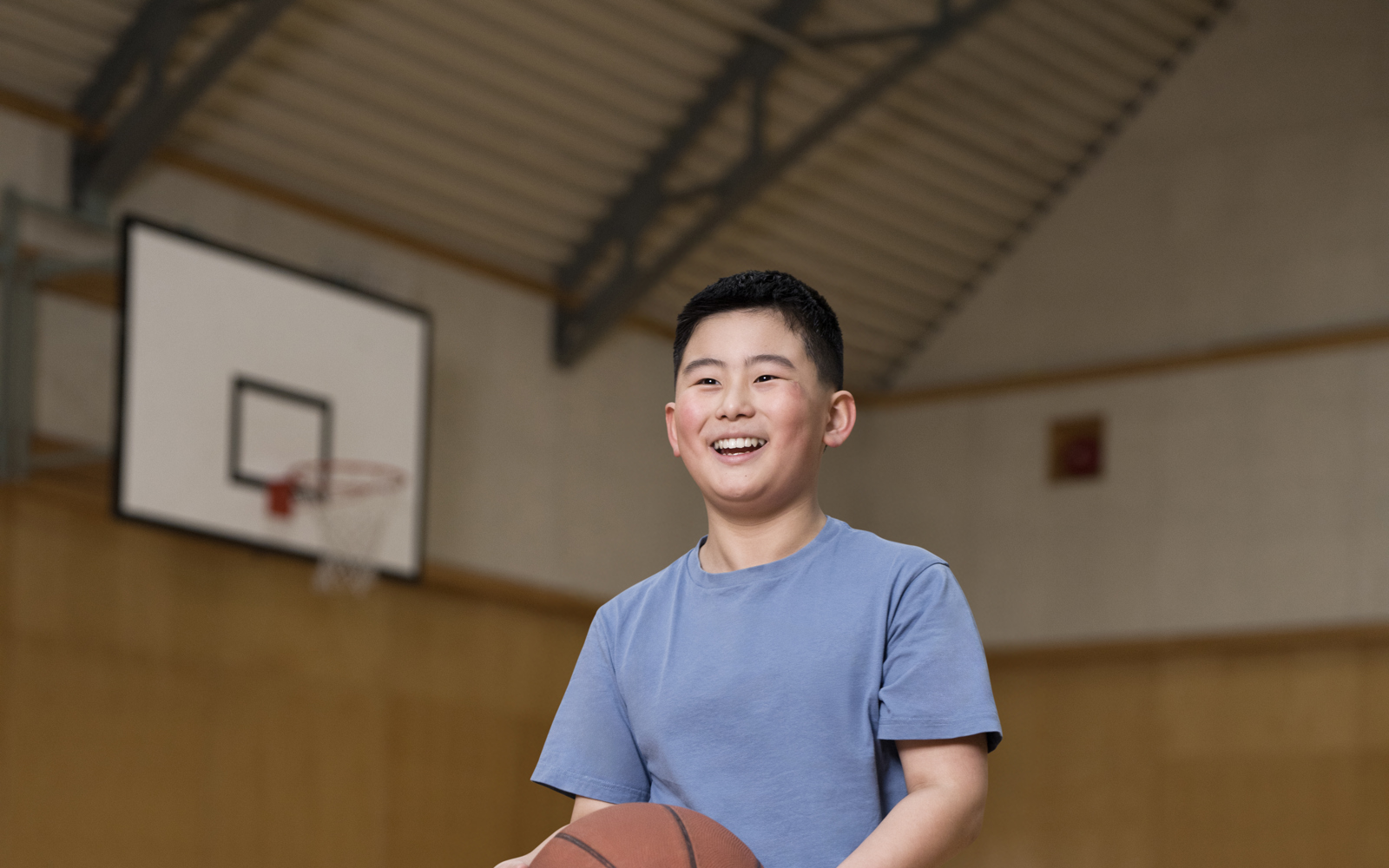 Jeune garçon en chemise bleue tenant un ballon de basket