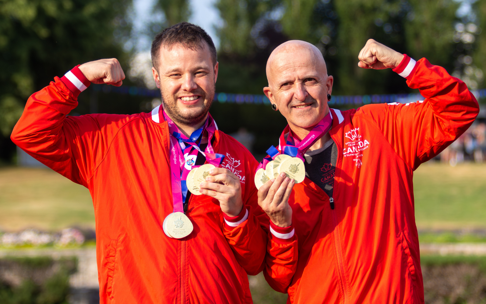 Two athletes in Team Canada uniforms with medals around their necks. 