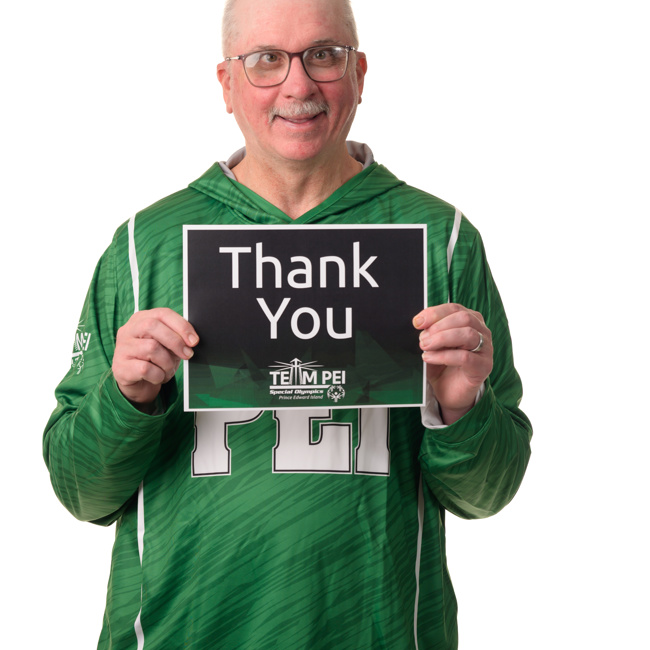 Team PEI 2026 Softball athlete, Tommy MacGuigan, standing with a thank you sign