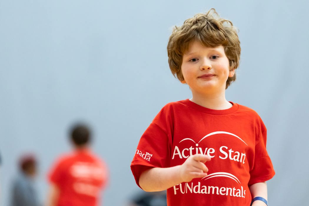 Jeune garçon aux cheveux bruns et vêtu d'un t-shirt rouge Enfact Actif courant vers la caméra.