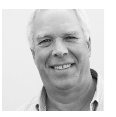 Black and white photo of a man smiling at the camera. 