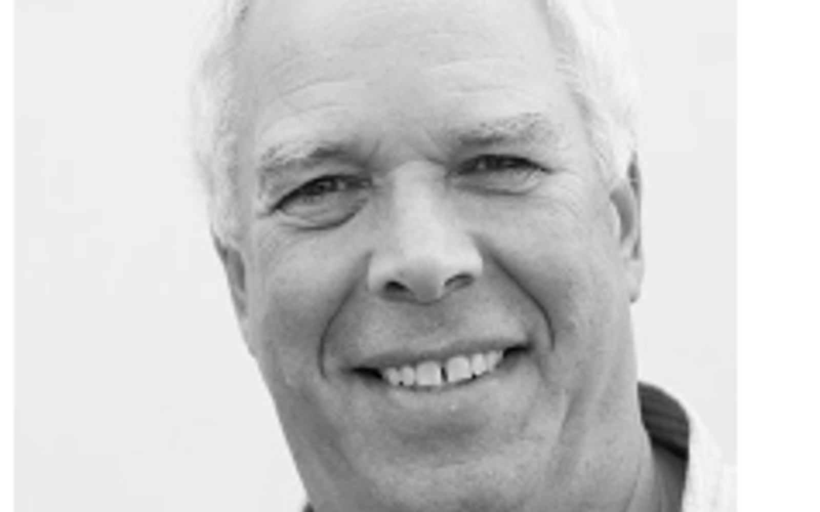 Black and white photo of a man smiling at the camera. 