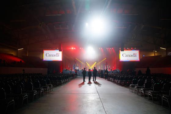 Trois personnes debout dans une pièce bondée avec la marque du gouvernement du Canada