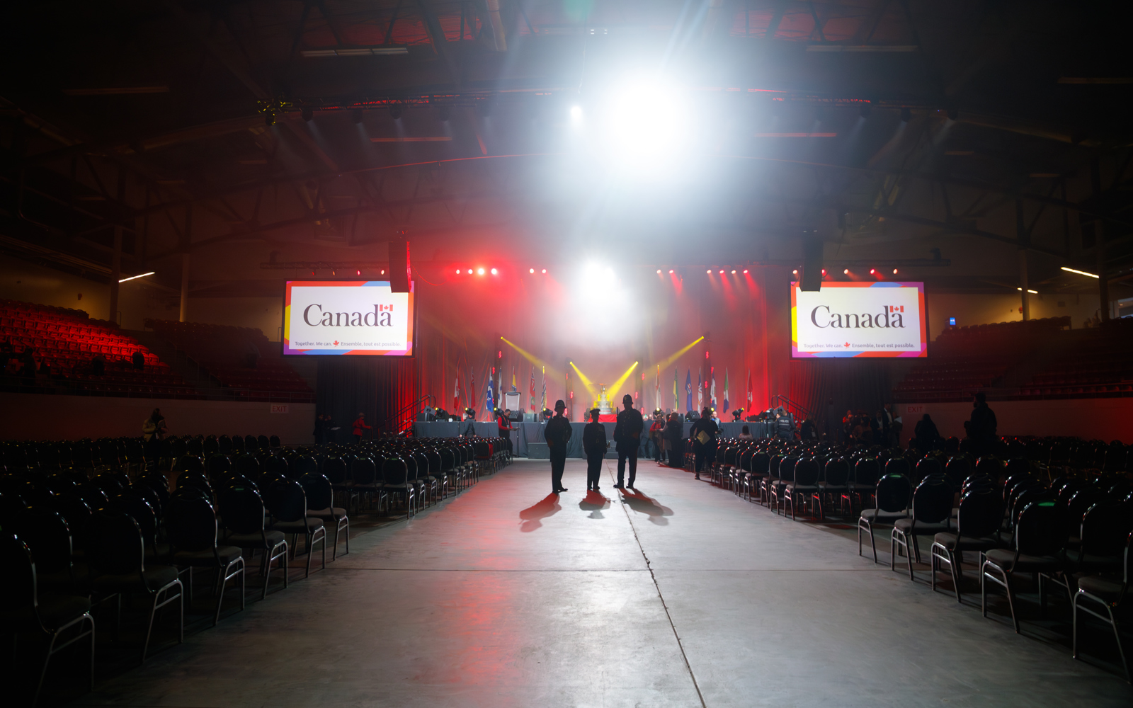 Three people standing in a crowded room with Government of Canada branding 