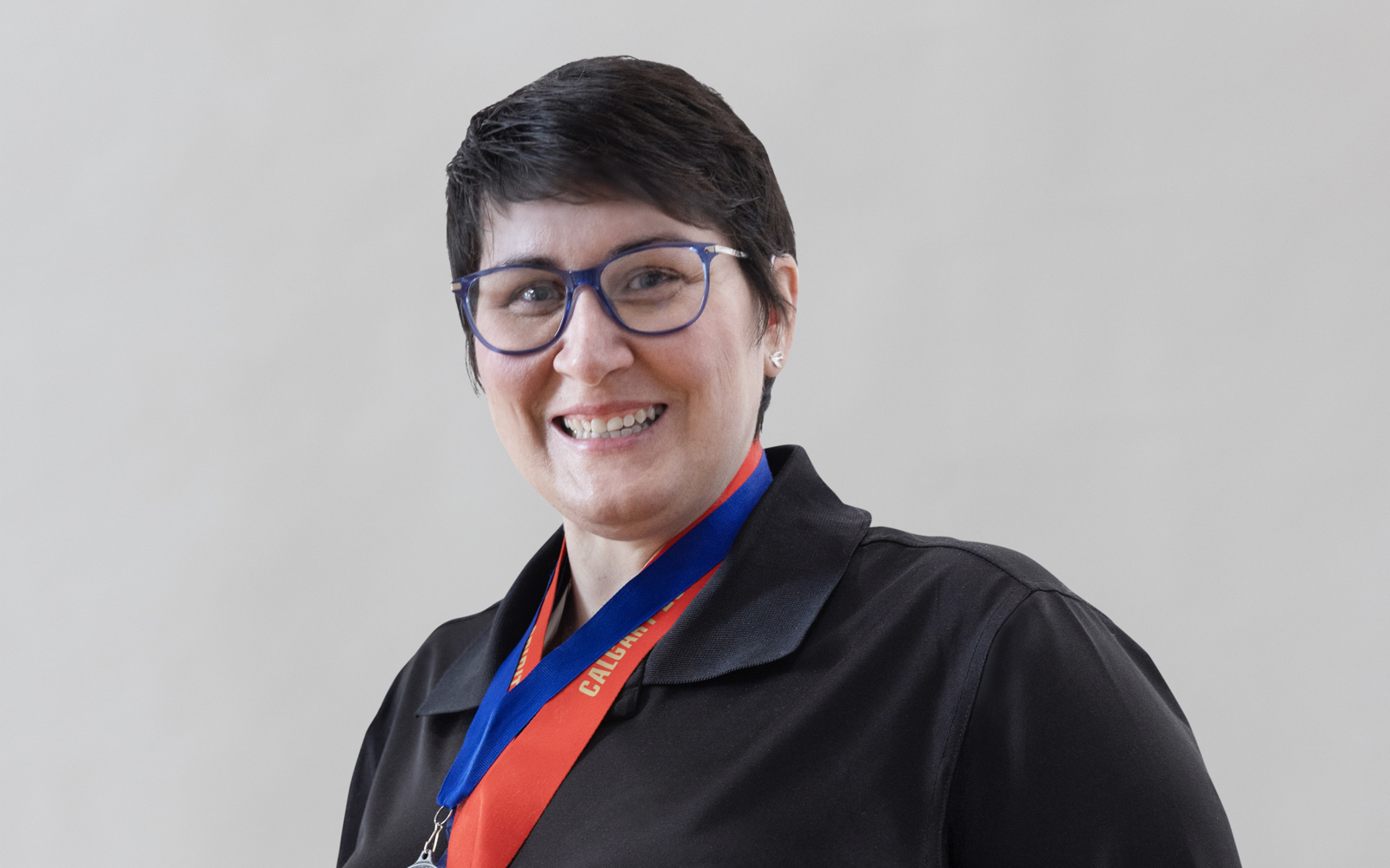 Women in a black shirt with a ton of medals around her neck 