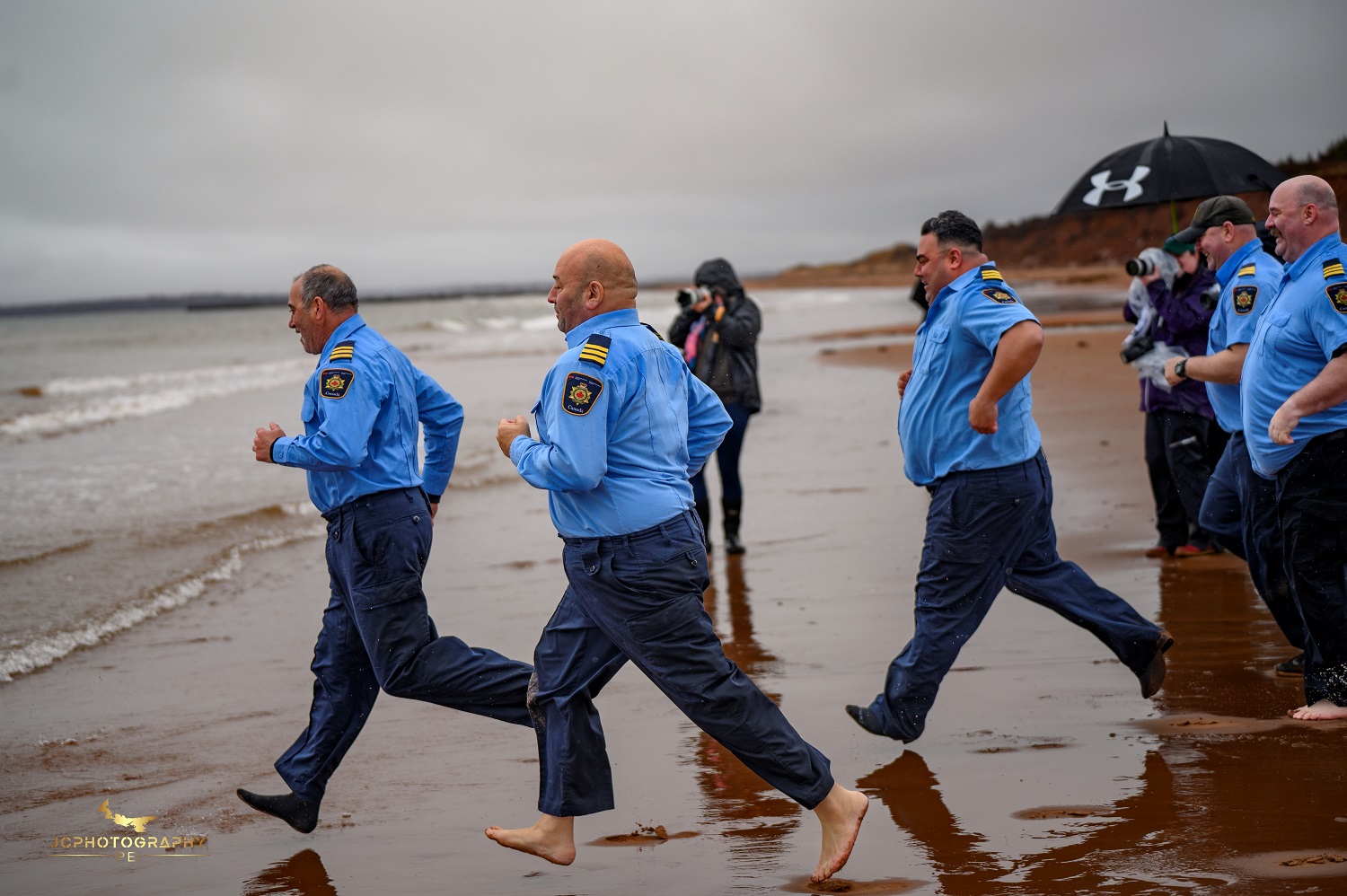 A group of people run into the water on the beach for a Polar Plunge event