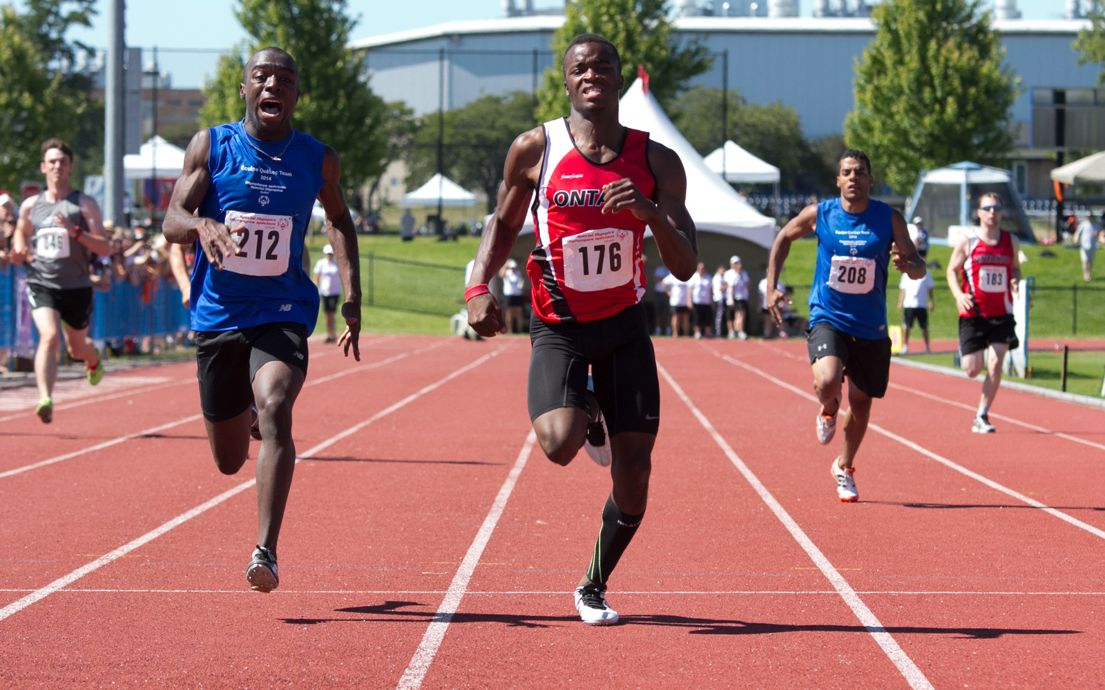 Two athletes running on a track. both are very focused on running. 