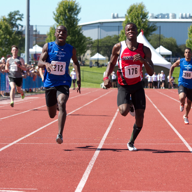 Two athletes running on a track. both are very focused on running. 