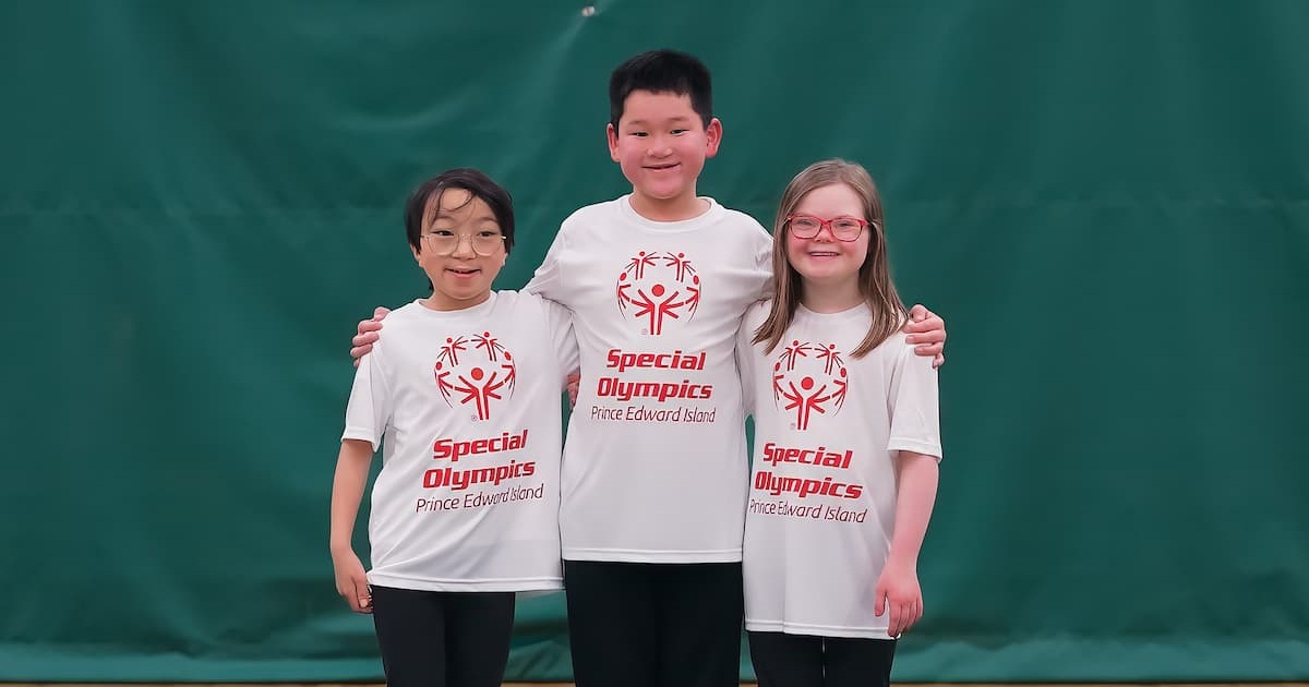 Three young kids stand in a line. All wearing Special Olympics white shirts and black pants. Three young kids stand in a line. All wearing Special Olympics white shirts and black pants.