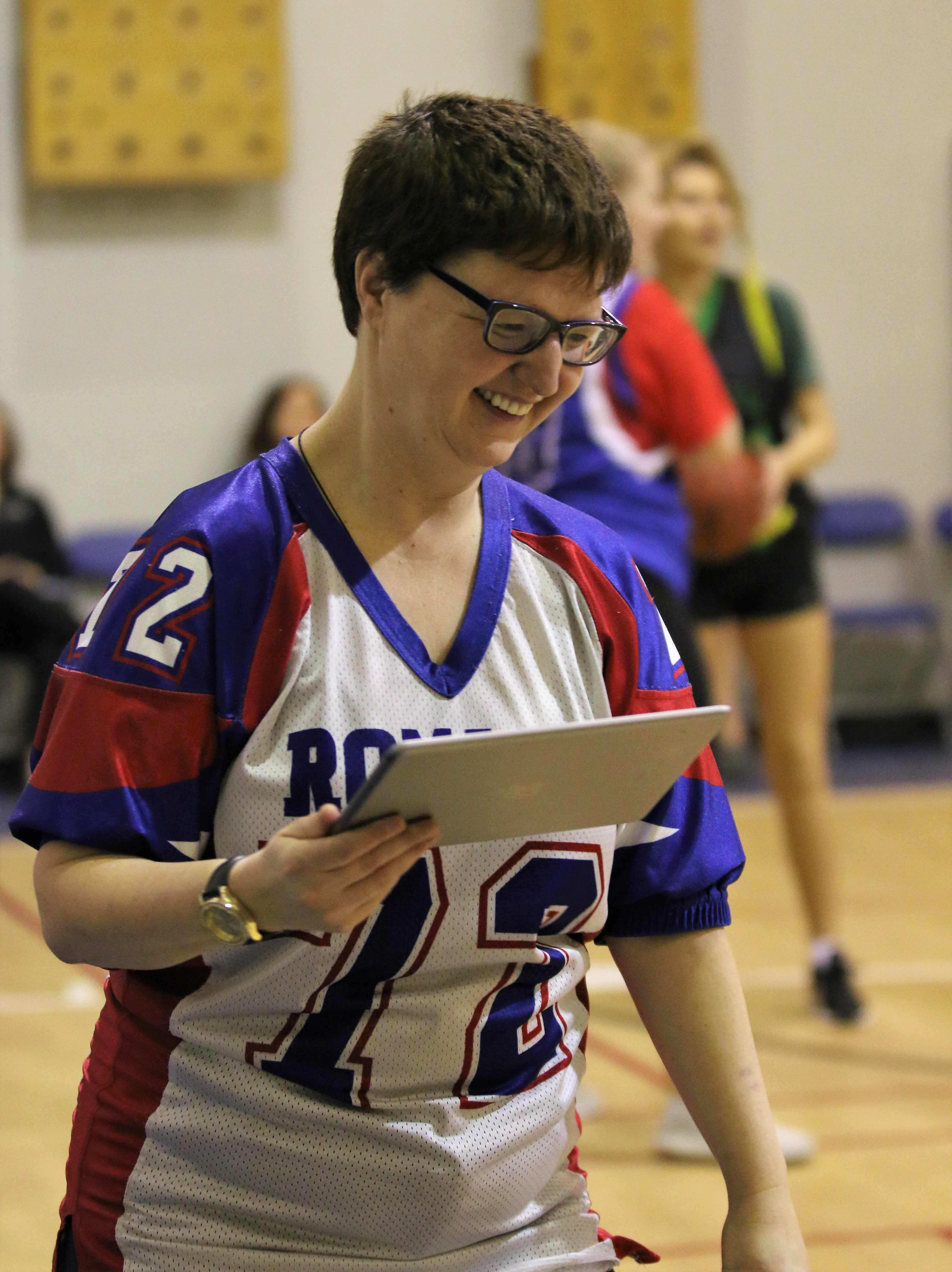 A closeup image of a volunteer holding an iPad. She is smiling and looking down.