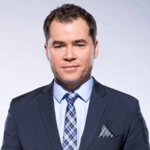 Man in blue suit, light blue shirt and blue plaid tie. 