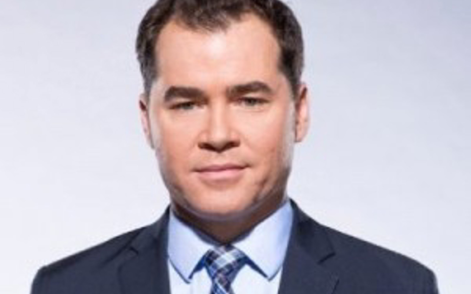 Man in blue suit, light blue shirt and blue plaid tie. 