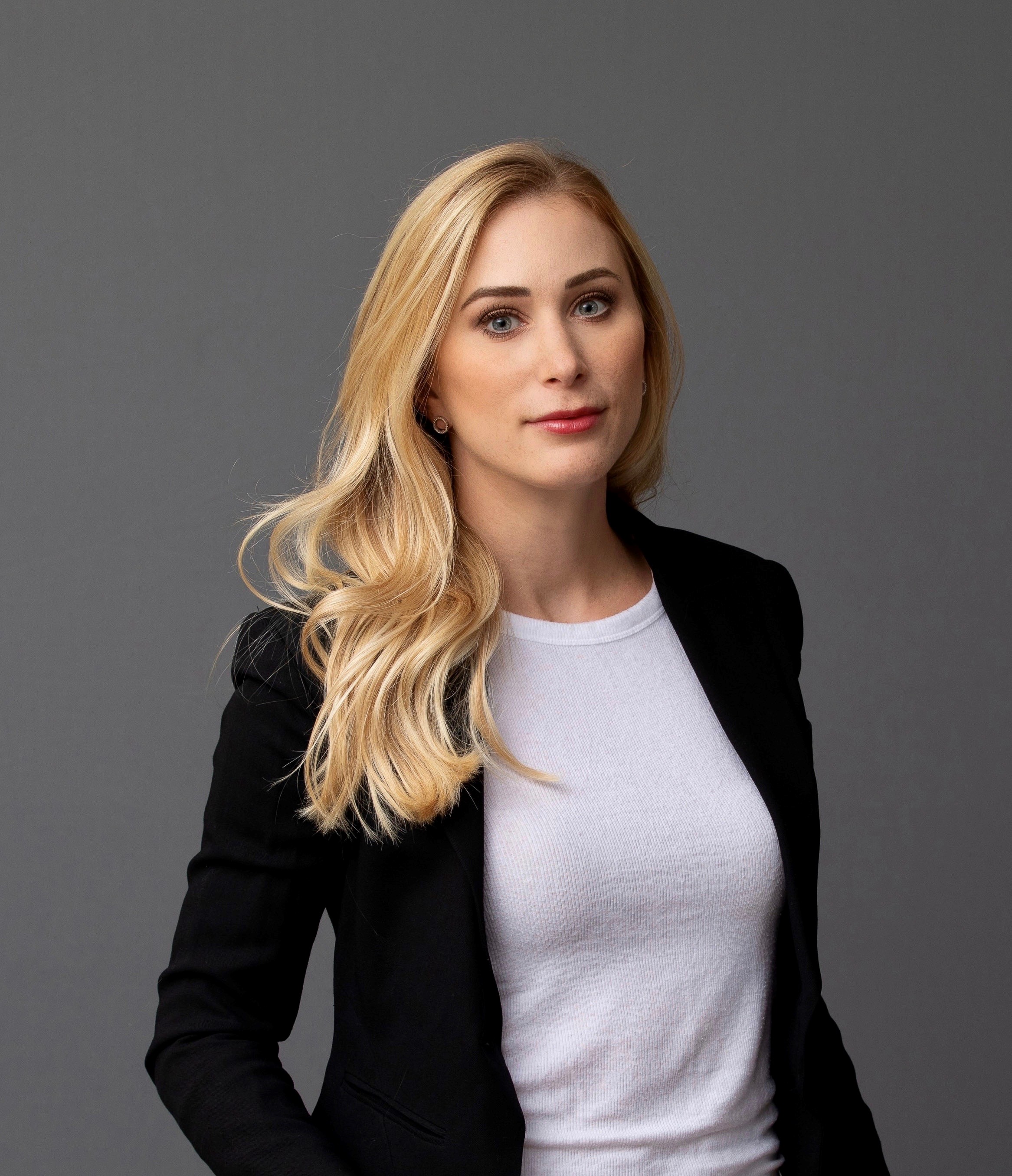 Portrait of a woman with long blond hair wearing a white sweater and a black blazer. Portrait of a woman with long blond hair wearing a white sweater and a black blazer.