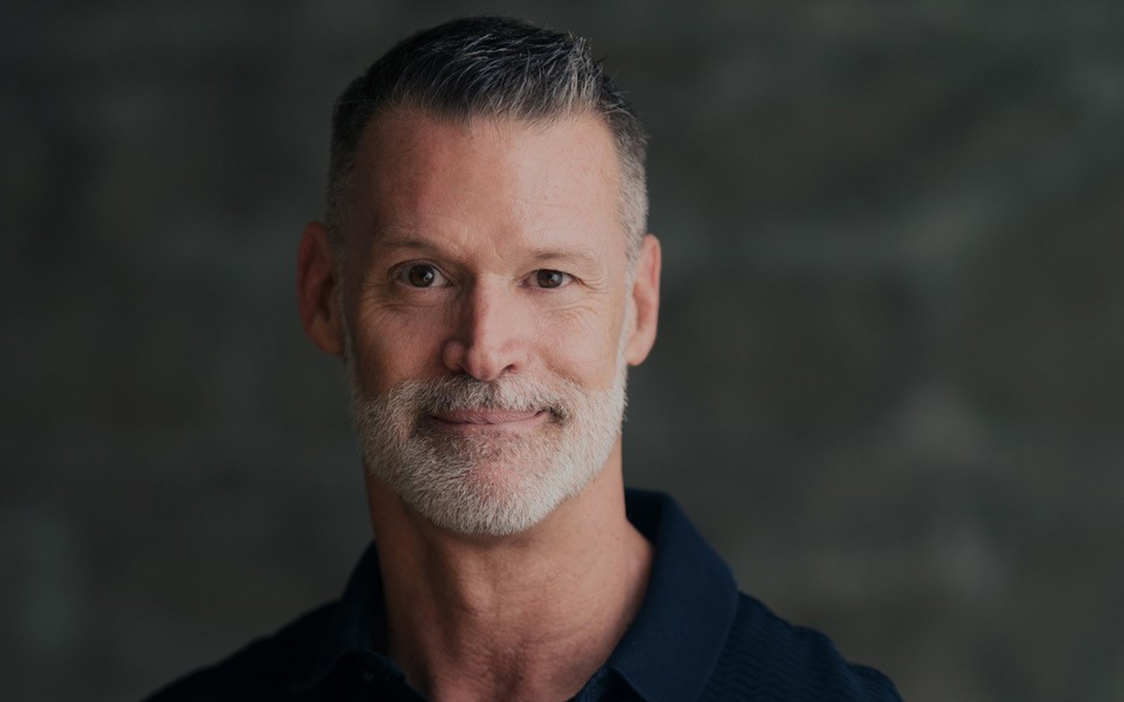 Portrait d'un homme portant un polo noir.