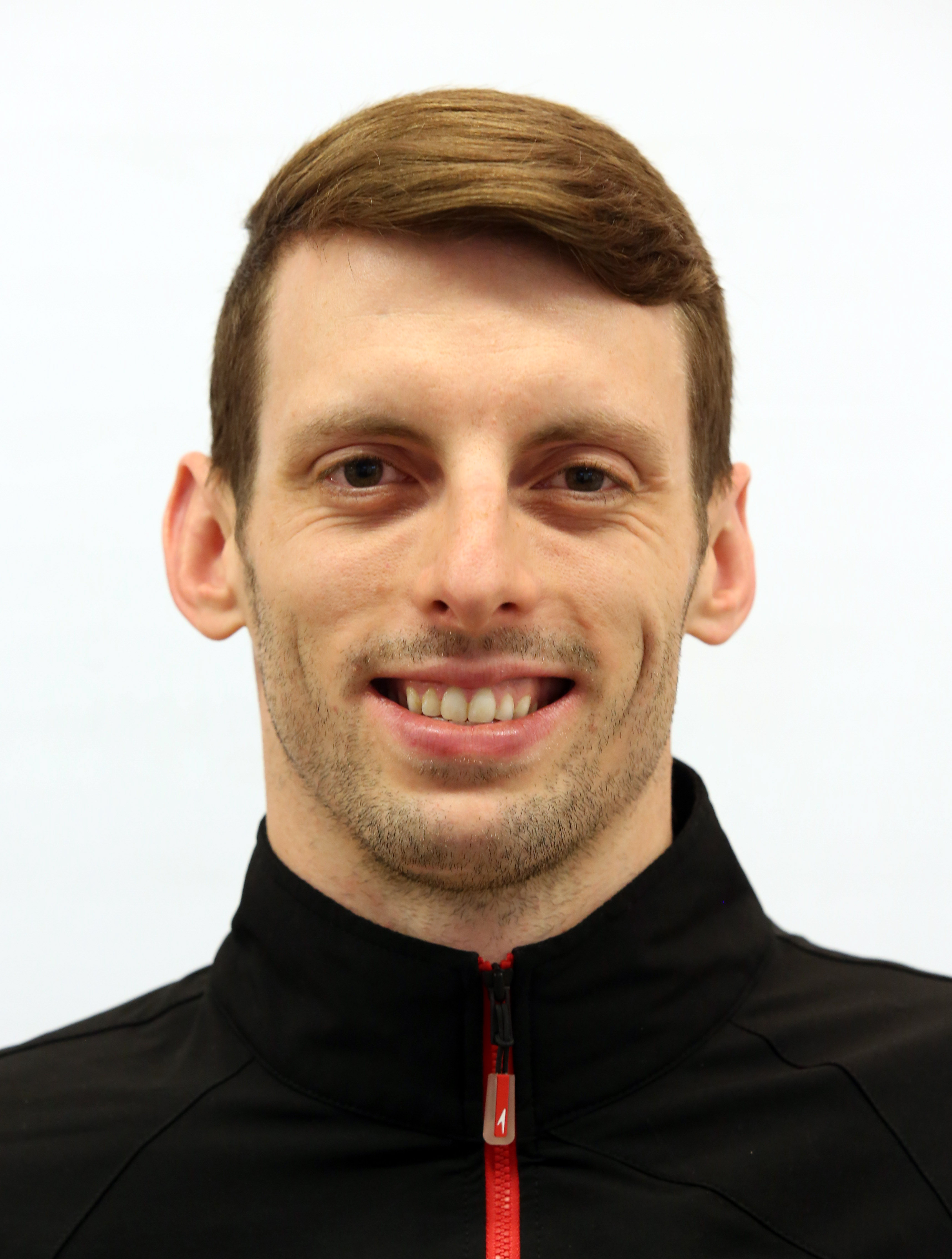 Headshot of a man in a black zip up. Headshot of a man in a black zip up.