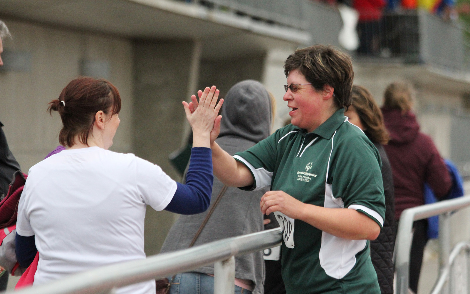 Special Olympics BC athlete high fives a fellow athlete after their race.