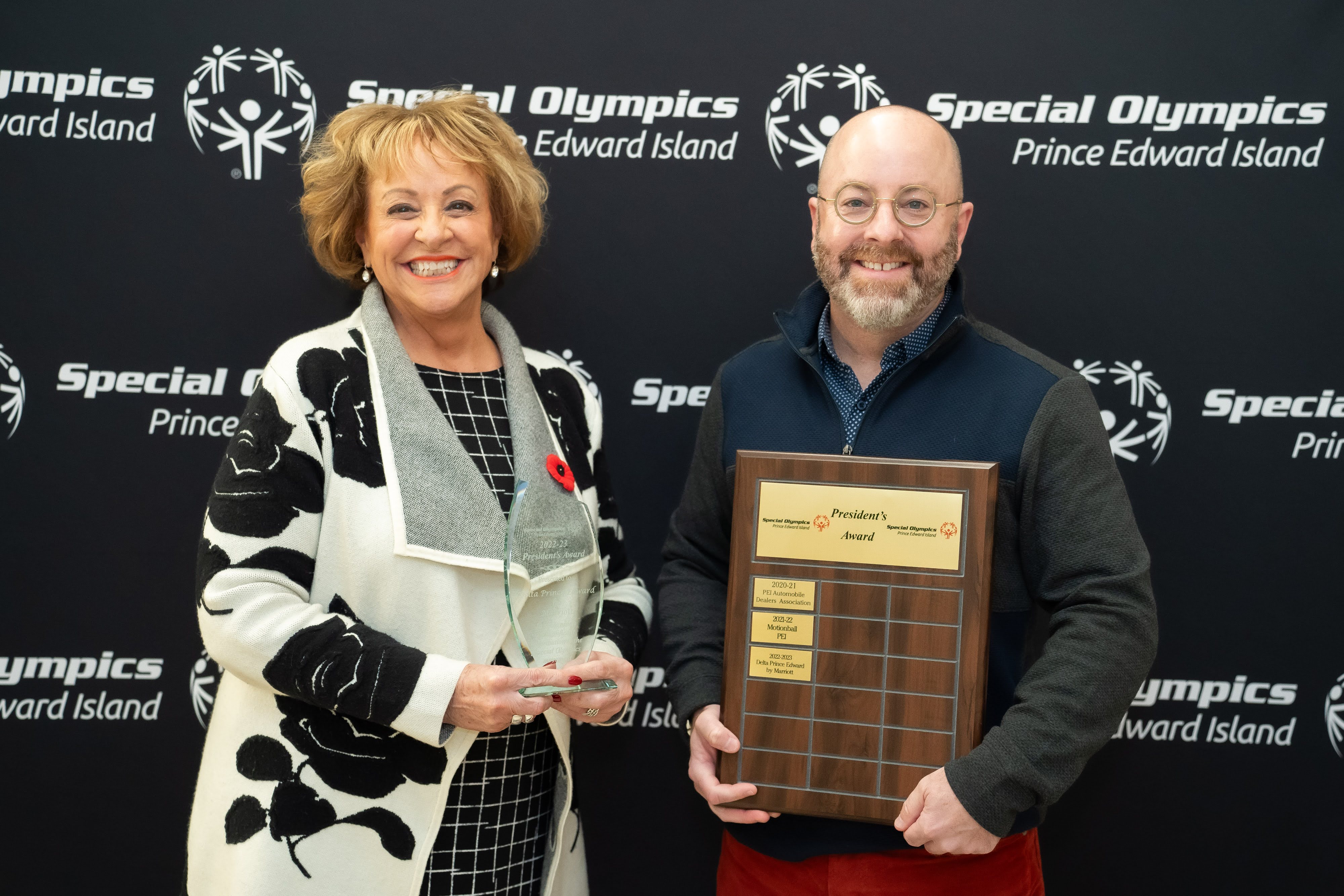 Volunteer Betty Anne is recognized at Special Olympics PEI's Annual Awards; 2 people standing in front of Special Olympics PEI's backdrop