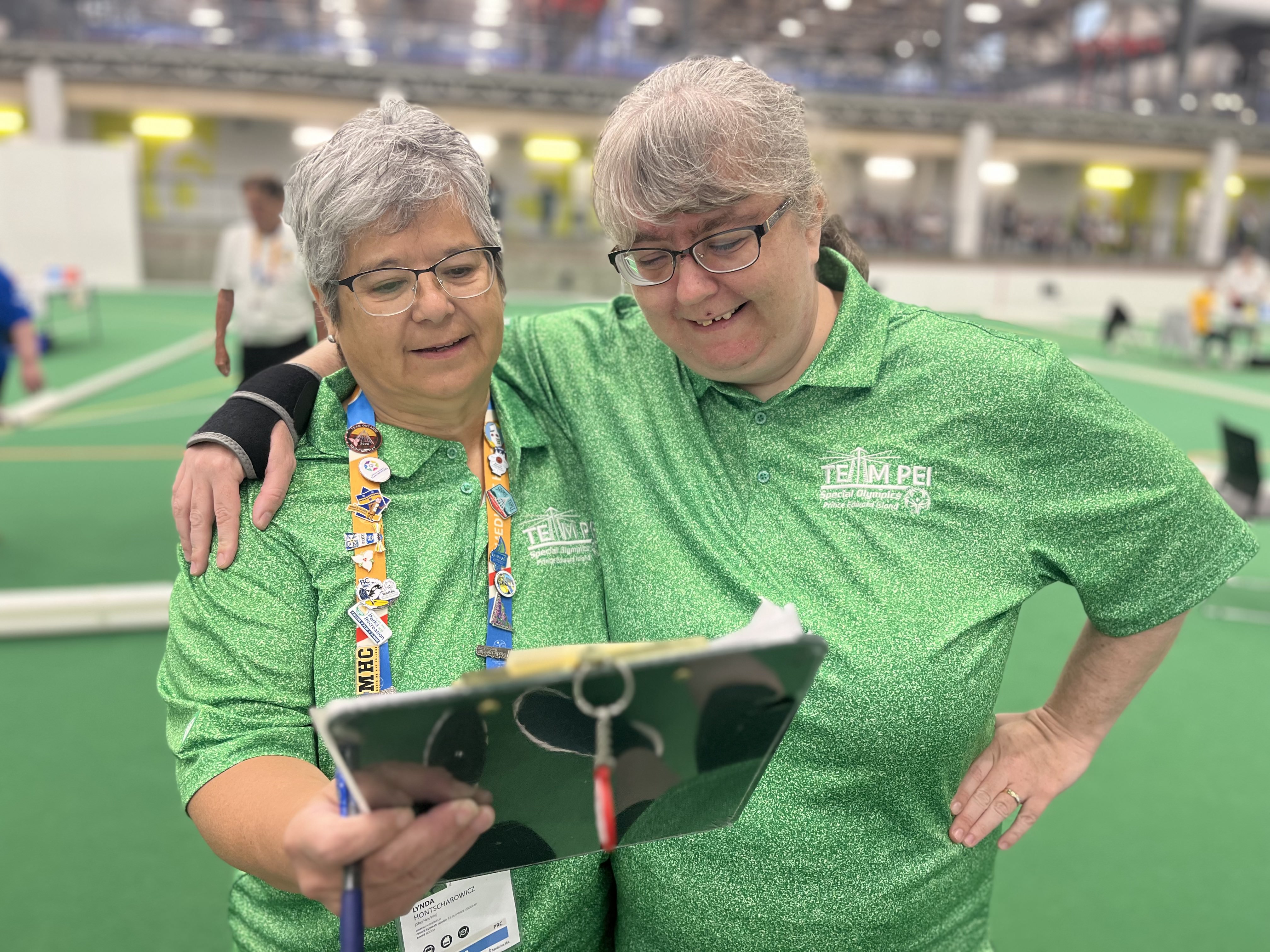 Athlete and volunteer standing toward looking at a clipboard Athlete and volunteer standing toward looking at a clipboard