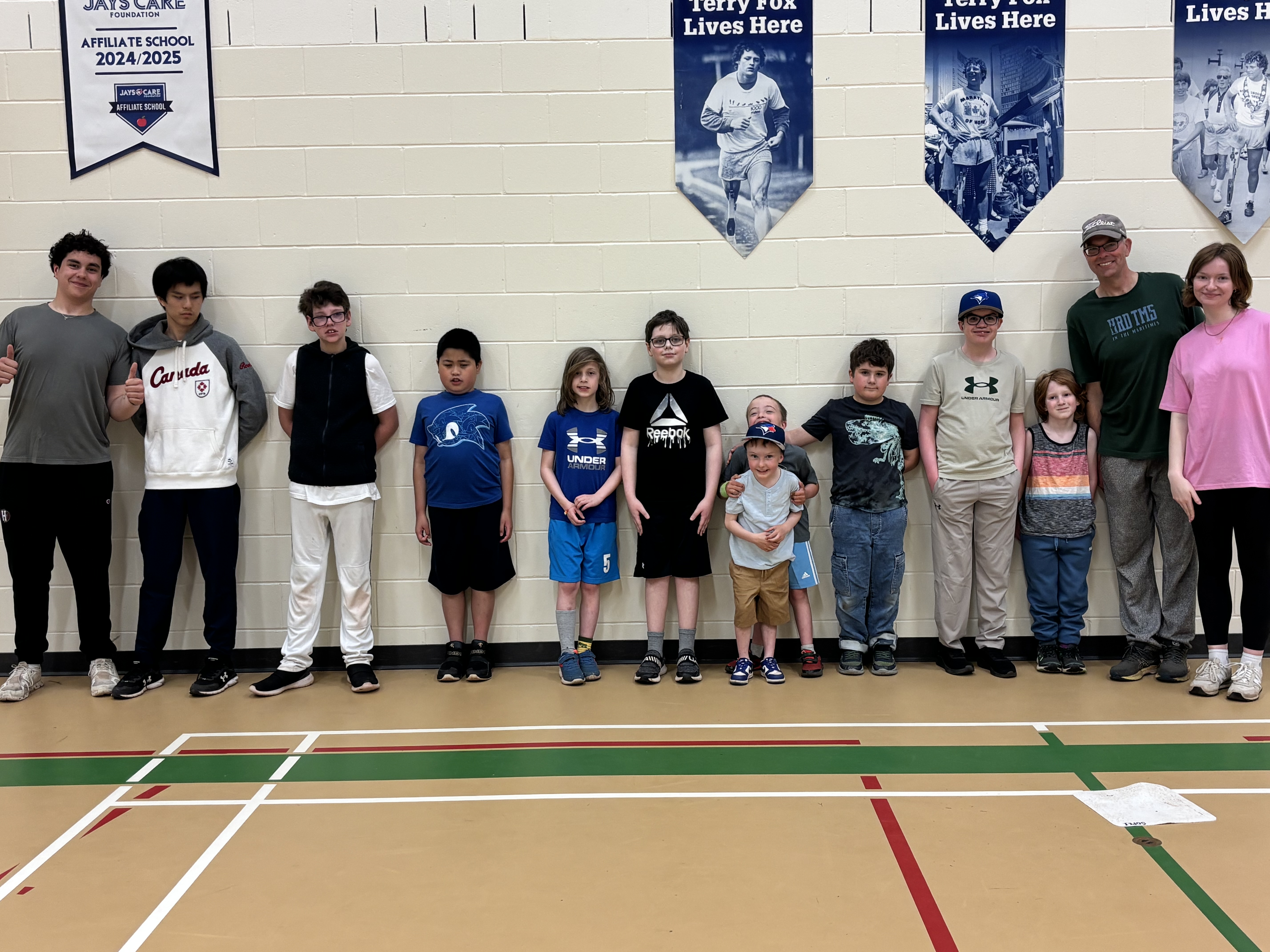 A group of youth softball athletes and volunteers standing in a gym