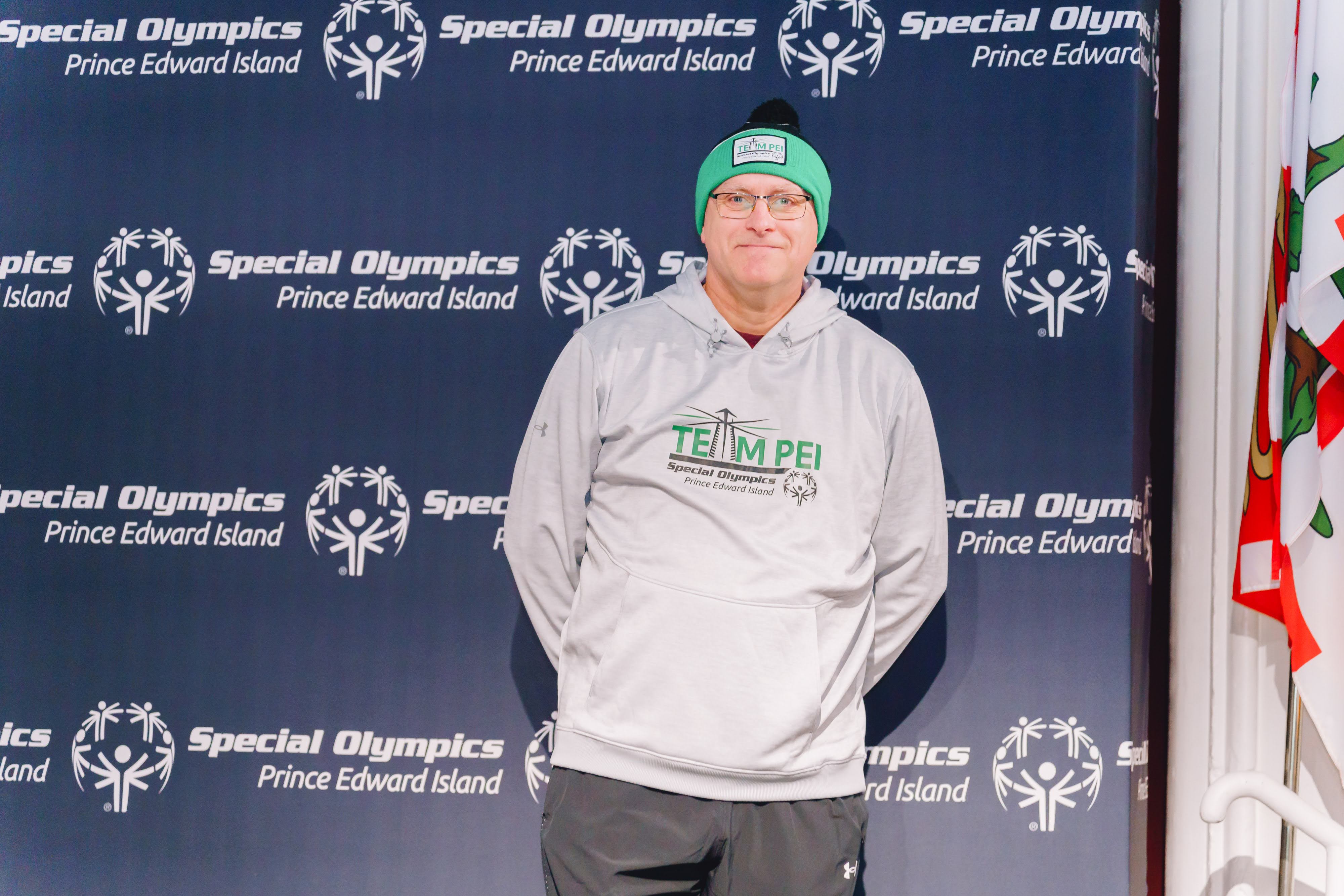 Team PEI Volunteer Larry Robbins in front of our Special Olympics Backdrop