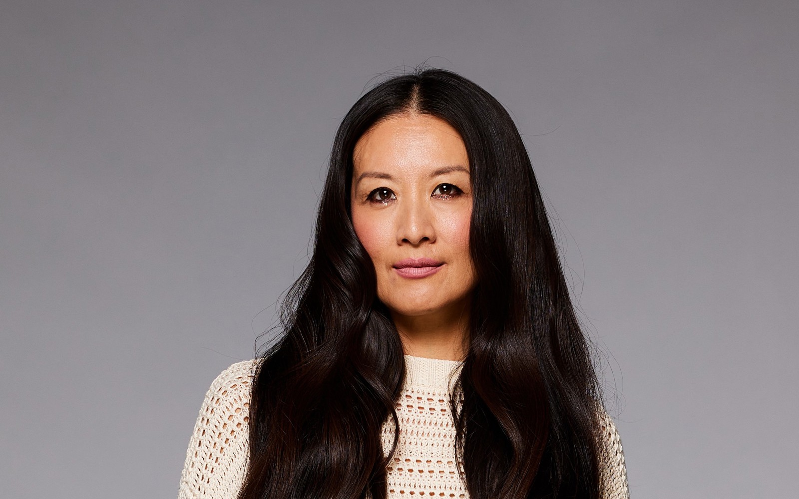 Femme aux longs cheveux foncés vêtue d'une robe blanche.