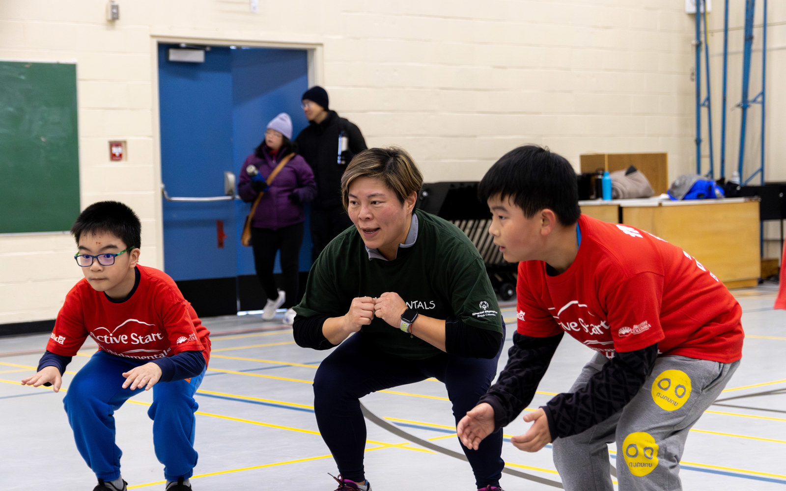 Two young boys with intellectual disabilities join their coach in warm-up exercises.