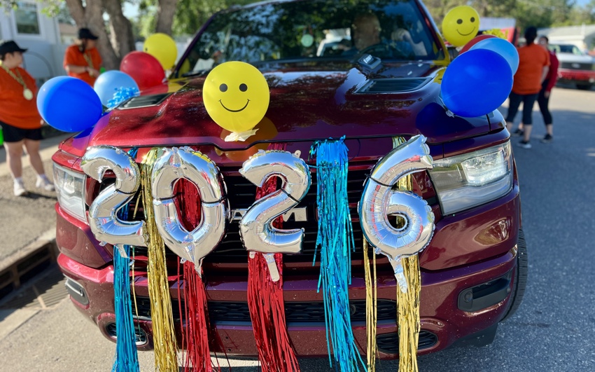 The front of a red pickup truck, decorated with streamers, "2026" balloons, and multicoloured balloons.